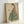 May include: Framed art print leaning against white wall showing woman in profile wearing green and white striped kimono with coral floral sleeve detail, holding orange persimmon fruit. Japanese-inspired illustration with muted earth tones on cream background in light wood frame.