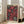 May include: Framed vintage-style poster with pink and black floral design featuring stylized sunflowers and polka dot patterns, displayed against white wall next to beige upholstered chair in bright modern living room with large windows and natural lighting.