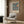 May include: Framed vintage William Morris exhibition poster featuring two orange and yellow birds perched among blue foliage, red strawberries, and cream flowers. Poster hangs on wood paneled wall above cream upholstered armchair with geometric pillow. Modern floor lamp and side table with open book complete the warm, sophisticated reading nook setting.