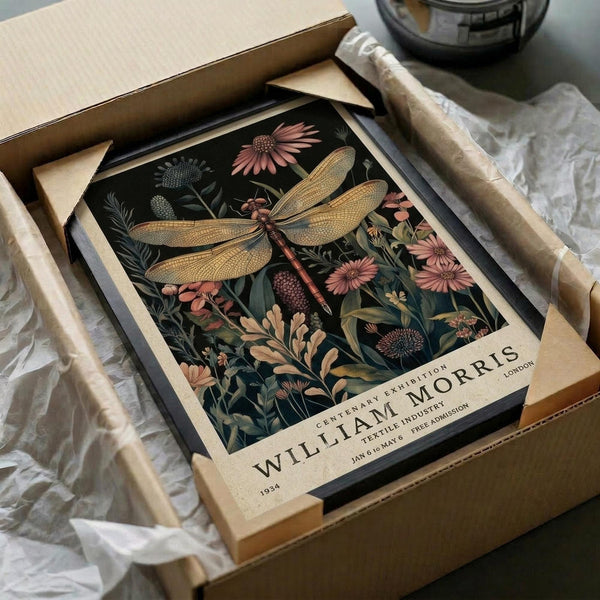 May include: Vintage botanical art print featuring a detailed dragonfly with golden wings surrounded by pink flowers and green foliage on dark background, displayed in black frame within cardboard packaging alongside wooden dowels and white tissue paper on neutral surface
