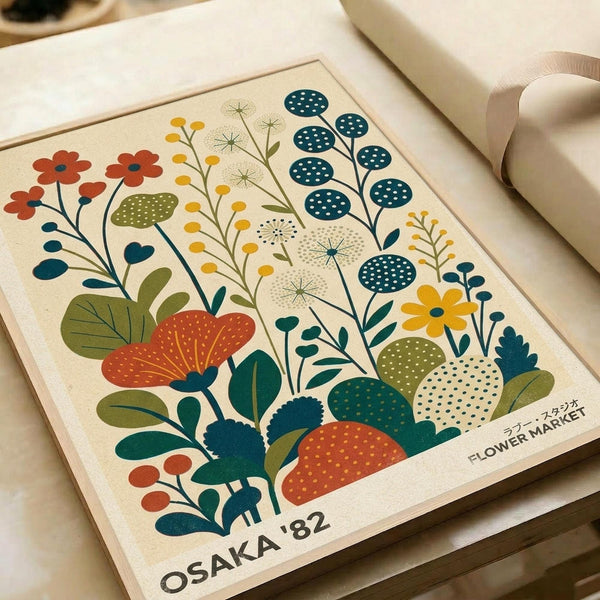 May include: A vintage-style botanical poster print featuring stylized flowers and plants in retro colors of teal, orange, olive green, and cream. The illustration shows various wildflowers, dandelions, berries, and foliage in a folk art style with dotted patterns and geometric shapes. Text reads "OSAKA '82 FLOWER MARKET" at the bottom. The print appears framed and is photographed against neutral paper wrapping materials.