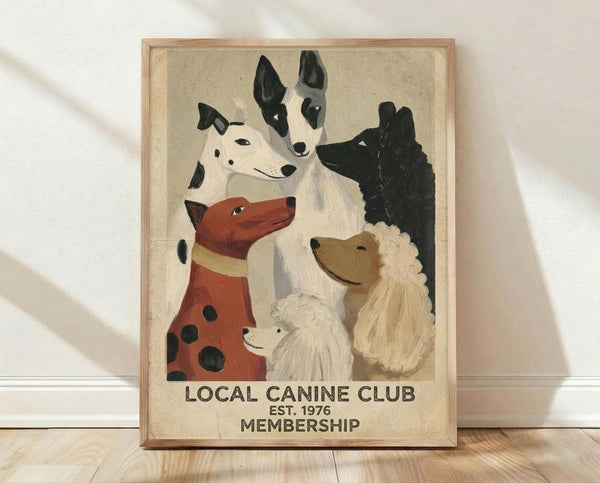 May include: Framed vintage-style poster with illustrated dogs of various breeds including dalmatian, husky, poodle, and others arranged in a group portrait style. Text reads "LOCAL CANINE CLUB EST. 1976 MEMBERSHIP" at bottom. Artwork has muted beige background with natural wood frame, displayed against white wall on light wooden floor with soft shadows.