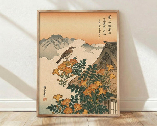 May include: Framed Japanese woodblock print reproduction featuring a small brown bird perched among orange trumpet vine flowers with green foliage, traditional thatched roof house, misty mountains in background, warm peach sky, vertical Japanese calligraphy text, red artist seal, displayed in light wood frame on wooden floor against white wall with natural lighting shadows.