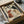 May include: Framed vintage-style poster featuring illustrated dog profiles in earth tones - black and white spotted dogs, reddish-brown dog, and golden retriever with text "Local Canine Club Est. 1976 Membership" at bottom. Black frame sits in open cardboard shipping box with white tissue paper and brown paper tube nearby on white surface.
