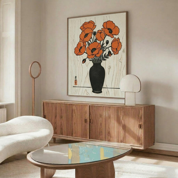 May include: Framed botanical print featuring orange poppies in black vase displayed above wooden sideboard in modern living room. White curved chair and glass-top coffee table visible. Artwork shows vintage Japanese woodblock style with cream background and natural wood frame.