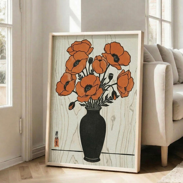 May include: Large framed botanical print leaning against white wall next to beige upholstered chair. Artwork shows orange-red poppies with dark centers in black vase against wood grain background, featuring Japanese woodblock print style with visible artist seal. Natural light streams through windows creating soft shadows on hardwood floor.