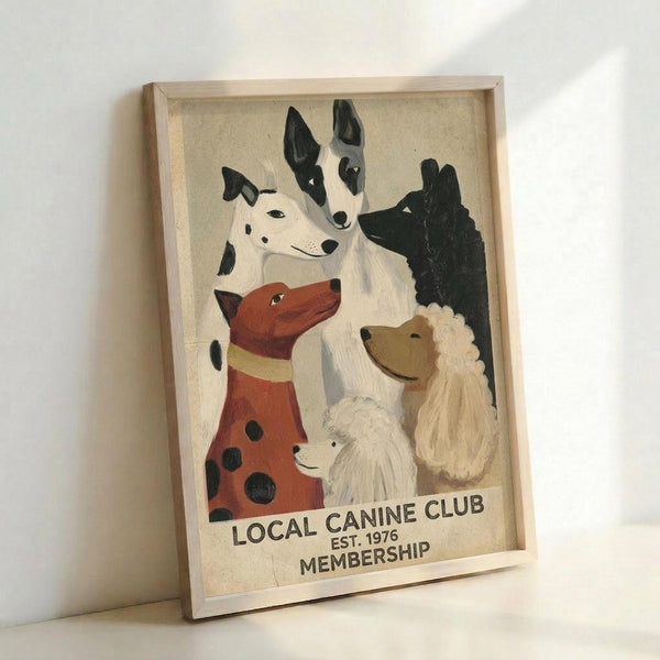 May include: Framed vintage-style poster featuring illustrated dogs in various breeds and colors including a spotted red dog, black and white dogs, and a fluffy light-colored poodle, with "LOCAL CANINE CLUB EST. 1976 MEMBERSHIP" text at bottom, displayed in light wood frame leaning against white wall
