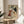 May include: Framed vintage-style poster featuring illustrated dogs of various breeds including dalmatian, bull terrier, and poodle on cream background, displayed on round wooden side table next to beige upholstered chair with plant leaves visible in soft natural lighting