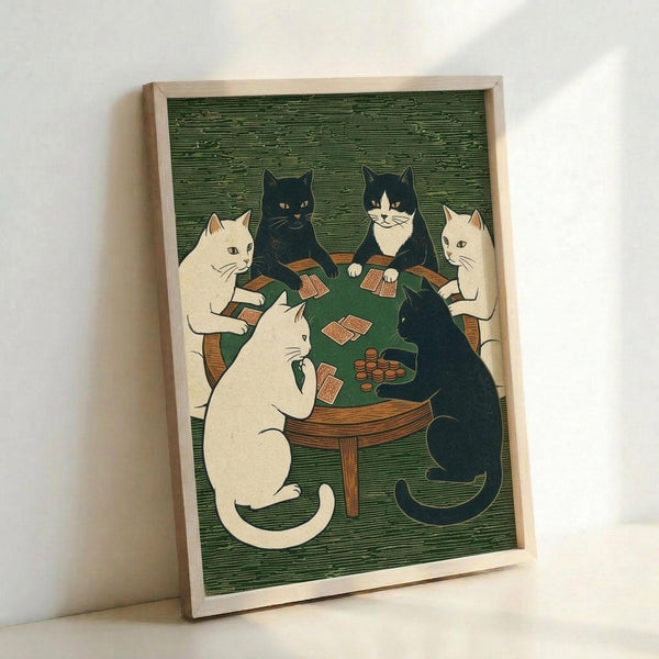 Framed art print showing six cats sitting around a wooden table playing cards in a woodblock print style. The cats include white, black, and black-and-white varieties positioned on wooden chairs around a green table surface with playing cards and poker chips. The artwork features a textured green background with horizontal line patterns reminiscent of traditional woodcut prints. The piece is displayed in a light wooden frame leaning against a white wall.