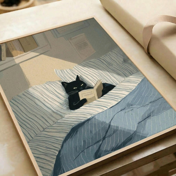 May include: Framed illustration of a black cat lying in bed reading a small book, surrounded by striped blue and white pillows and bedding. The artwork shows a cozy bedroom scene with warm lighting and papers on the wall. The print is displayed in a light wood frame on a cream colored surface next to a white tube, showing how the poster might look when framed and styled in a home setting.