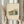 May include: Person holding framed modernist architectural print showing geometric building design in green, orange and blue tones. Light wood frame with cream matting, held alongside dried pampas grass stems against soft neutral background with window lighting.