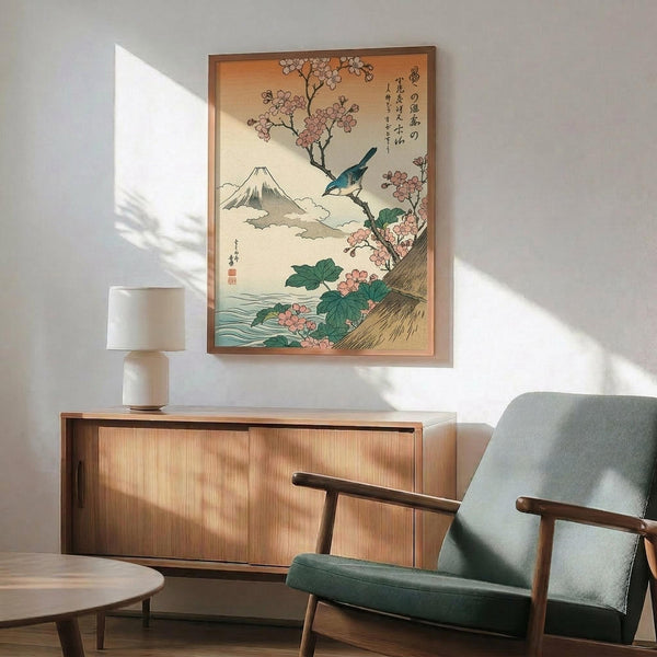 May include: Japanese woodblock print artwork in wooden frame showing Mount Fuji, cherry blossoms, and blue bird, displayed above mid-century modern walnut credenza with ceramic table lamp, next to sage green upholstered armchair in bright sunlit room with white walls.