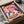 May include: Whimsical artwork showing two geese wearing sunglasses sharing pizza and wine on a pink background, displayed in a black frame nestled in brown cardboard packaging with white tissue paper protection.