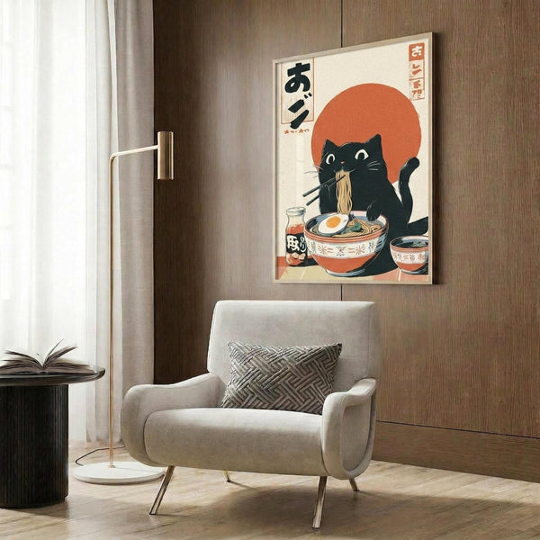 May include: Japanese-style poster print displayed on wood-paneled wall above beige upholstered armchair. Artwork features black cat eating ramen noodles with chopsticks against orange sun background, with Japanese text and traditional ukiyo-e art style. Modern living room setting includes geometric patterned pillow, brass floor lamp, and dark side table with open book.