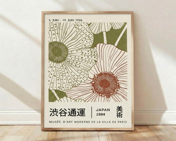May include: Framed vintage-style botanical poster featuring two stylized flowers with dotted and striped petals in olive green and rust orange colors against cream background. Japanese and French text visible below artwork. Natural wood frame sits on light wooden floor against white textured wall with soft shadows.