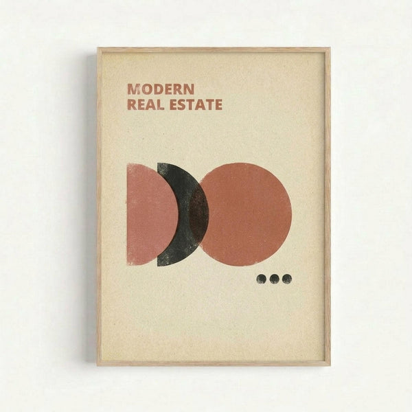 Framed minimalist poster with cream background featuring abstract geometric design of overlapping circles in dusty pink, terracotta orange, and charcoal black, with "MODERN REAL ESTATE" text at top and three small dots below the shapes, displayed in light wood frame against white wall