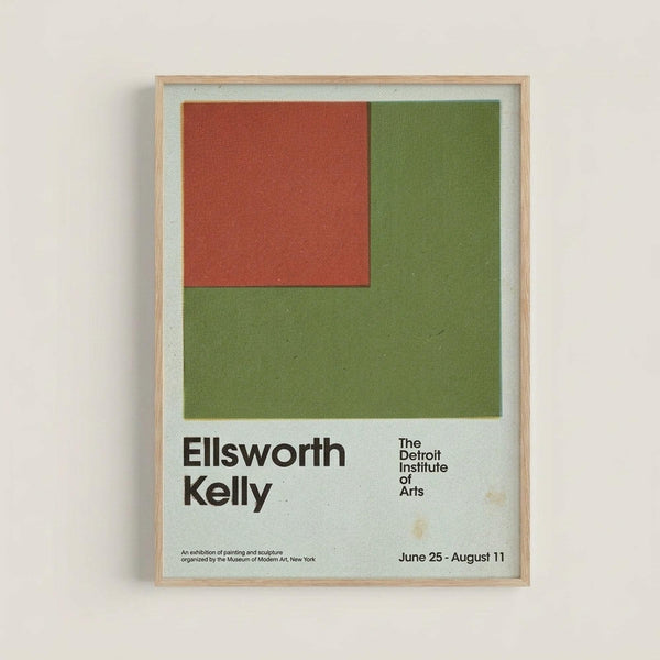 Framed exhibition poster featuring geometric shapes in rust red and olive green on light background. Shows artist name "Ellsworth Kelly" and "The Detroit Institute of Arts" with exhibition dates June 25 - August 11. Natural wood frame hangs on white wall with visible texture and subtle aging spots on the poster surface.
