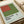 May include: Vintage exhibition poster for Ellsworth Kelly at The Detroit Institute of Arts, featuring abstract geometric blocks in rust red and olive green on pale background. Poster is matted in cream frame, positioned on white surface next to rolled papers and ceramic objects in soft natural lighting.
