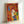 May include: Framed colorful dog illustration artwork leaning against white wall. The print features four stylized dogs in vibrant colors - orange with blue ears, white with pink ears, yellow with green ears, and blue with orange ears - arranged in an overlapping composition against warm red and yellow background. Light wood frame with visible texture and brushstroke-style artistic treatment throughout the design.