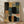 May include: Abstract geometric artwork in wooden frame leaning against white wall on hardwood floor with palm leaf shadows. Features overlapping rounded rectangles in black, sage green, dusty blue, coral orange, and cream with textured brushstroke appearance in modern minimalist room setting.