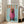 May include: Framed poster featuring a brown dachshund wearing a pink knit hoodie on a light blue background with "DOGUE" text in orange letters, displayed against white wall next to beige sectional sofa in bright living room with hardwood floors and large windows