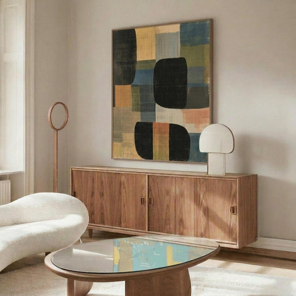 May include: Abstract geometric artwork displayed above walnut credenza in modern living room. Poster features overlapping rounded rectangles and squares in muted tones of sage green, dusty blue, coral pink, cream and black on textured background. Room styled with curved white chair, brass floor lamp, oval glass coffee table and white table lamp.