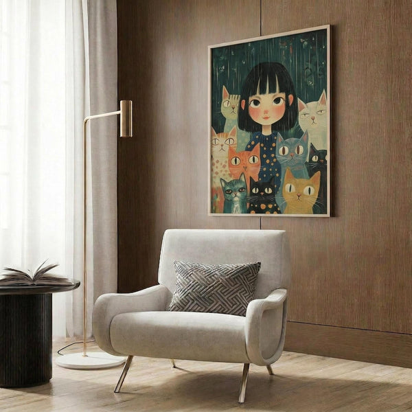 May include: Framed poster artwork displayed on wood-paneled wall above beige upholstered armchair with geometric pillow. Artwork shows young girl with black bob haircut surrounded by multiple cats in various colors including orange, gray, white and black, set against teal background with falling rain. Modern reading nook with brass floor lamp and side table.