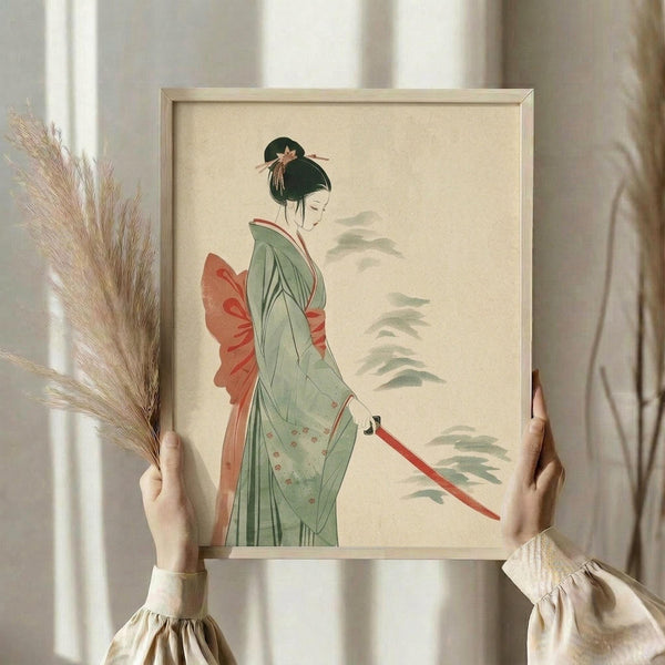May include: Person in cream ruffled sleeves holding framed artwork depicting Japanese woman in sage green kimono with coral obi sash, holding red katana sword. Traditional ukiyo-e style illustration with muted tones and misty background elements. Natural wood frame against white curtained window, dried pampas grass visible to left.