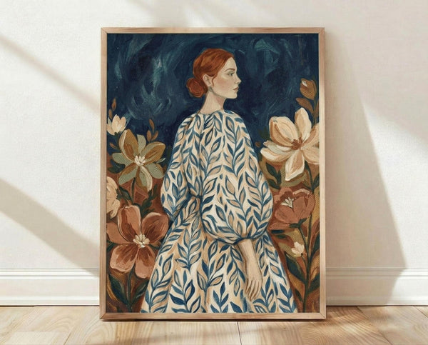 May include: Framed artwork leaning against white wall on light wooden floor. The print shows a woman with red hair in a bun, wearing a cream dress with blue leaf pattern, surrounded by large brown and cream flowers against a dark blue background. Natural lighting casts soft shadows on the textured wall.
