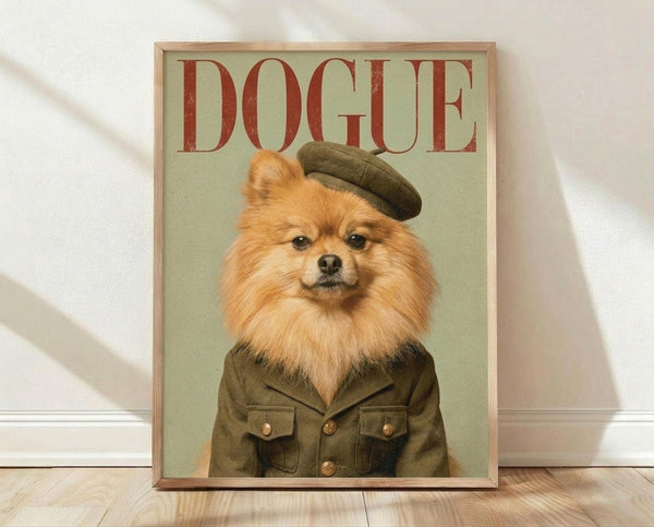 May include: Framed poster print leaning against white wall on light wood floor. Shows orange Pomeranian dog wearing olive green military-style jacket with brass buttons and matching beret on sage green background. Red "DOGUE" text at top mimics fashion magazine cover style. Natural wood frame, portrait orientation, casting soft shadows on textured white wall.