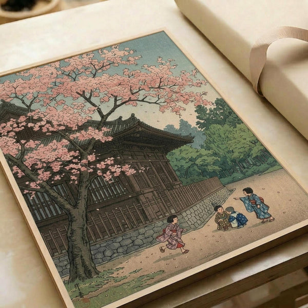A vintage Japanese woodblock print showing a traditional temple building with curved rooflines surrounded by a large cherry blossom tree with pink blooms. Four figures in colorful kimonos walk along a stone-paved path in the foreground, with scattered pink petals on the ground. The scene features muted colors including soft pinks, greens, and earth tones typical of ukiyo-e art style. The print appears on cream paper with a ribbon visible in the corner.