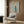 May include: Framed poster print showing a cream-colored poodle wearing a teal turtleneck sweater and small boots, styled as a fashion magazine cover with "DOGUE" text at top. The artwork is displayed on wood-paneled wall above a beige upholstered armchair with geometric patterned pillow. Modern brass floor lamp and side table with open book complete the sophisticated interior setting.