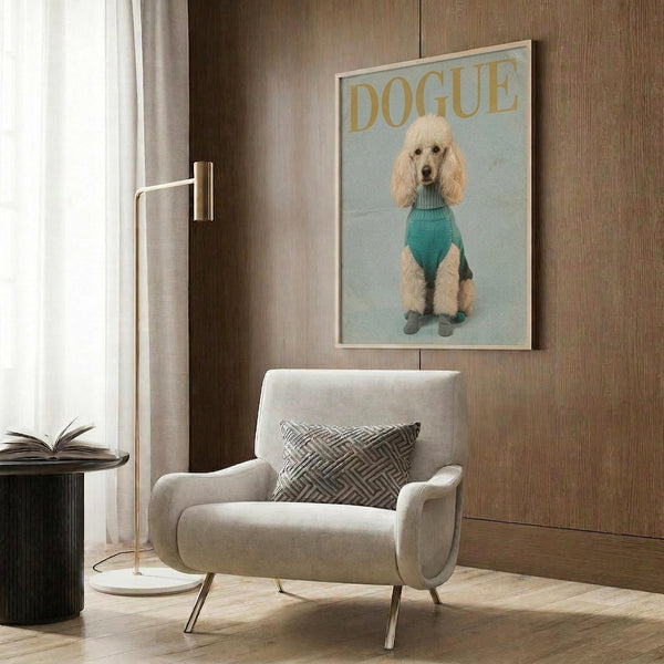 May include: Framed poster print showing a cream-colored poodle wearing a teal turtleneck sweater and small boots, styled as a fashion magazine cover with "DOGUE" text at top. The artwork is displayed on wood-paneled wall above a beige upholstered armchair with geometric patterned pillow. Modern brass floor lamp and side table with open book complete the sophisticated interior setting.