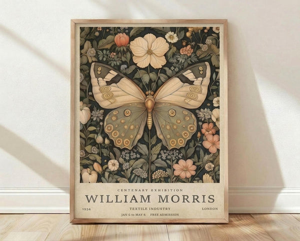 May include: Framed poster featuring a large butterfly with detailed wing patterns in earthy tones surrounded by botanical elements including flowers and foliage on a dark background. Text below reads "Centenary Exhibition William Morris" with exhibition details. Natural wood frame sits on light wooden floor against white textured wall with soft shadows.