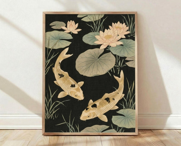 May include: Framed Japanese-style artwork featuring two golden koi fish swimming among pink lotus flowers and large green lily pads against a dark background. The print shows delicate water plants and reeds in muted tones. Natural wood frame displayed on light wooden flooring against white wall with soft shadows.