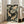 May include: Framed vintage-style Japanese artwork featuring two golden koi fish swimming among pink lotus flowers and large green lily pads on a dark background, displayed on wooden floor next to beige upholstered chair in bright room with white walls and windows.