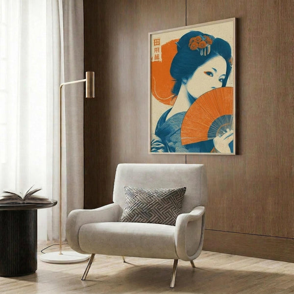 May include: Japanese-style poster print featuring a woman in blue kimono holding an orange folding fan, mounted in light wooden frame on wood-paneled wall. Modern living room setting with beige upholstered chair, geometric patterned pillow, gold floor lamp, and dark round side table. Warm neutral color palette with natural lighting from window.