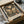 May include: Vintage-style botanical poster featuring a large butterfly with circular wing patterns surrounded by flowers and foliage in muted earth tones of beige, coral, and olive green on dark background. Framed print shown in cardboard shipping box with protective wrapping on white tissue paper beside cardboard tubes, suggesting careful packaging for delivery.