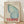 May include: Framed vintage-style poster with light blue butterfly wing design against cream background, featuring red Japanese text vertically aligned on left side, "The Rising Wind" in script, and bold red "TOKYO" text at bottom with "JAPAN 1977". Natural wood frame displayed on light wooden floor against white wall with soft shadows.