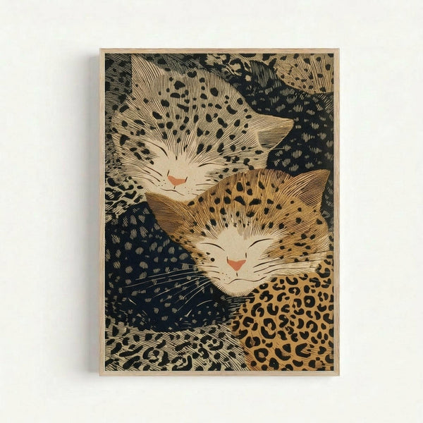Vintage Japanese woodblock print artwork featuring two sleeping cats with peaceful expressions nestled together. The cats display spotted and leopard-like patterns in warm golden tones against a dark blue background with intricate crosshatched texturing. The print is matted in a light wooden frame and mounted on a white wall, showing the traditional ukiyo-e art style with fine line work and organic flowing forms throughout the composition.