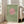 May include: Framed art print leaning against beige armchair in bright living room with white walls and windows. Green textured background with pink circle and black bird silhouettes flying across it. Light wood frame, approximately 2-3 feet tall, positioned on wooden floor next to furniture.