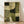 May include: Framed abstract poster with geometric shapes in earth tones of olive green, cream, and dark forest green. The artwork features curved and angular forms with textured, weathered appearance and grid-like patterns. Displayed in light wood frame leaning against white wall on natural hardwood floor with soft window light creating shadows.