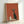 May include: Framed poster print leaning against white wall showing stylized black cat with white chest and wide eyes sitting beside cream-colored coffee pot and mug on table surface, all set against warm rust orange background in mid-century modern illustration style with natural wood frame