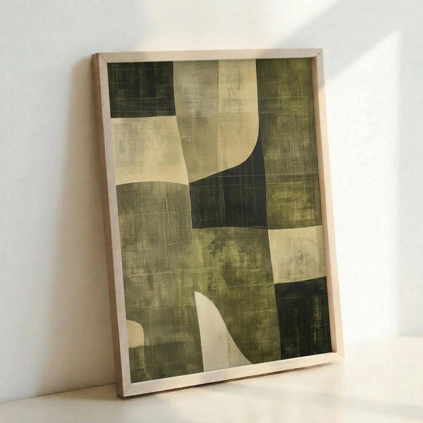 May include: Framed abstract art print leaning against white wall, featuring geometric composition in earth tones of olive green, cream, and dark forest green with curved organic shapes overlaying angular grid-like textures, displayed in light wooden frame on white surface