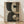 May include: Abstract geometric art print in natural wood frame leaning against white wall on light wooden floor. Artwork features overlapping curved and circular shapes in dark green and cream tones with weathered, textured surfaces. Soft natural lighting creates diagonal shadows across the scene.