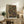 May include: A framed geometric art print featuring overlapping circles in earth tones of rust, sage green, and cream against a dark background, displayed on a rustic wooden sideboard alongside books, pottery, and a fern plant in a cozy living room setting with neutral walls and leather furniture.