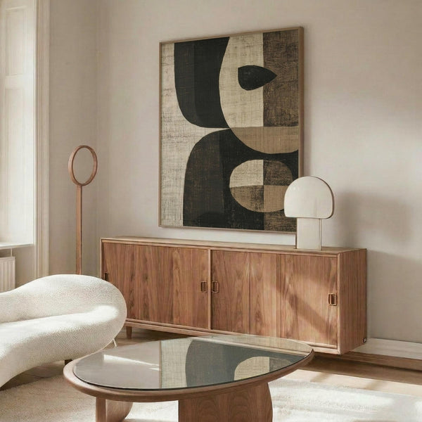 May include: Abstract geometric poster with dark green and cream colored curved and angular shapes displayed above a wooden sideboard in a modern living room setting with white upholstered chair, glass coffee table, and table lamp