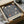 May include: Vintage exhibition poster with William Morris floral pattern in navy blue and cream, featuring ornate botanical designs with large blooms and flowing vines. Poster displayed in black frame, packaged in brown cardboard box with tissue paper wrapping on white surface.
