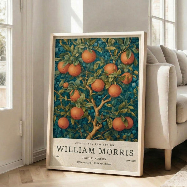 May include: Framed botanical poster with orange fruit tree design on deep blue background, displayed on wooden floor next to beige upholstered chair in bright room with white walls and windows. The vintage-style artwork features detailed branches, green leaves, and round oranges in warm tones, with exhibition text below the illustration.