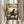 May include: Hands holding a framed anime poster showing a dark-haired samurai character in red robes wielding a sword in a bamboo forest setting. The poster features Japanese text and "A clash of styles. A journey with no map." tagline. Golden wooden frame against white curtained window background, with dried pampas grass visible on left side.